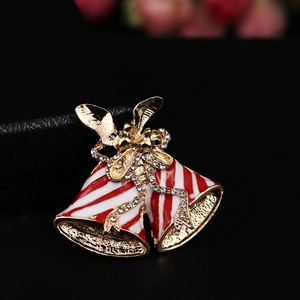 Macro detail of Christmas bell brooch with red white enamel and gold bow with crystals