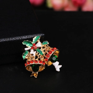 Macro detail of Christmas bell brooch with red crystals and green enamel foliage