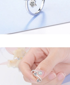 Detail of silver star-shaped open ring featuring a pearl accent and a sleek metal finish