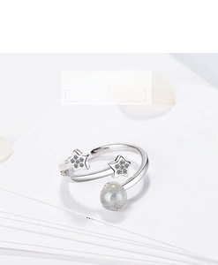 Macro shot of silver open ring with zircon star motifs and a round moonstone gem