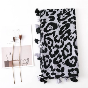 Close-up of leopard print scarf with fringe details next to a minimalist magazine