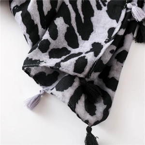 Detail of leopard print scarf featuring dual-color tassels and refined fabric texture