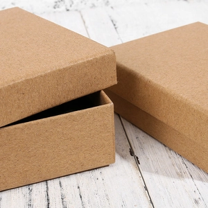Macro shot of square brown kraft paper jewelry gift boxes on white wood background