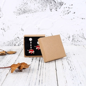 Red heart pearl earrings with LOVE text in a kraft paper jewelry box detail view