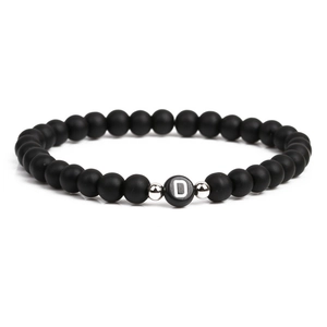 Detailed macro view of 6mm matte black stone beads with silver spacers and letter D charm