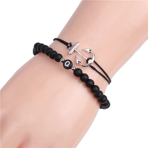 Detail of beaded matte black stone bracelet with silver anchor pendant on a wrist