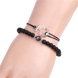 Close-up of black matte bead bracelet with silver anchor charm and letter F bead on wrist