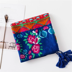Détails d'un châle à imprimé floral avec motifs ethniques et bordures à pompons bleu marine