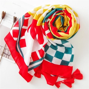 Détail d'une écharpe en coton imprimée avec des glands rouges et des motifs à carreaux