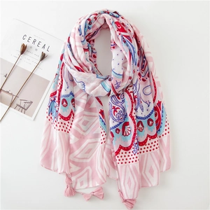 Détail d'un châle bohème rose avec imprimé ethnique, motifs floraux et pompons