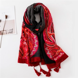 Détail d'un châle en coton à motif paisley rouge et noir avec des franges élégantes en bas