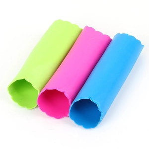 Trois éplucheurs d'ail en silicone de couleur vert, rose et bleu sur fond blanc
