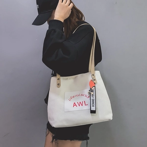 Detailed view of white canvas tote with brown faux leather handles and cute girl charm
