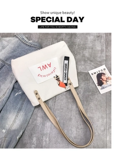 Top view of white canvas tote bag with red lettering, teddy charm, and leather straps