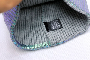 Detail view of metallic knit beanie inner stitching and 100% acrylic material label