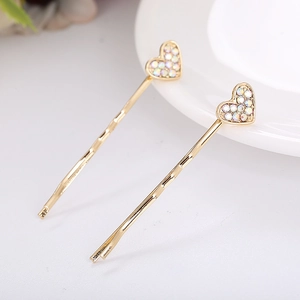 Close-up of golden hair clips with heart design and colorful rhinestones in a pair