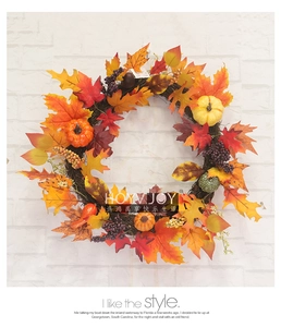 Detail of autumn wreath with maple leaves, mini pumpkins and berries on a white brick wall