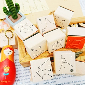Detail of wooden zodiac stamps featuring Gemini and Pisces signs on soft orange rubber
