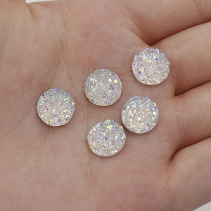 Detail shot of 10mm iridescent resin cabochons on a hand showing size and texture