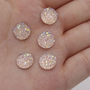Macro shot of 10mm resin druzy crystals with iridescent pink shimmer in a hand palm