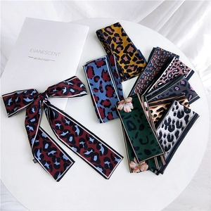 Assorted leopard print skinny silk scarves displayed elegantly on a minimalist white surface