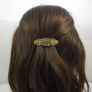 Detail van vintage bronzen metalen haarklem met reliëfpatronen in bruin haar