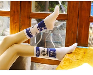 Dettaglio calzini in cotone blu e bianco con motivi di mucca e grafica a tema latte