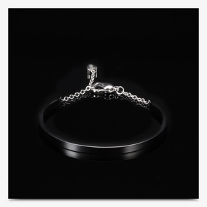 Detail of U-shaped black and silver bangle with heart pendant and lobster clasp closure