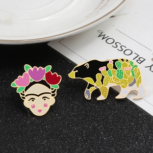 Artistic Frida Kahlo portrait and floral bear enamel brooch pins on a stylish background