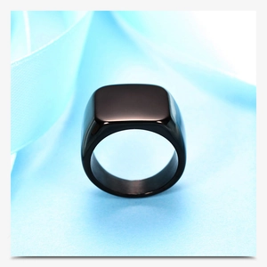 Macro shot of polished black square signet ring displayed on blue silk fabric