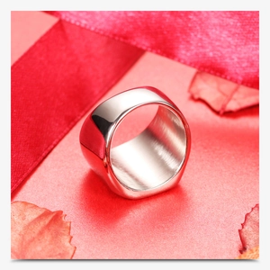 Detailed close-up of polished stainless steel wide band ring on a red gift background