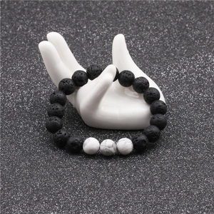 Close-up of 10mm lava stone and white turquoise beaded bracelet on ceramic hand display
