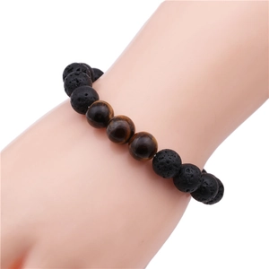 Macro detail of 10mm lava rock and tiger eye beaded bracelet on a model wrist