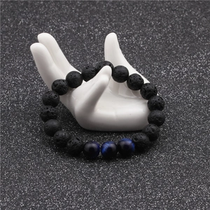 Macro view of 10mm volcanic lava and blue tiger eye stone beads on a ceramic hand display