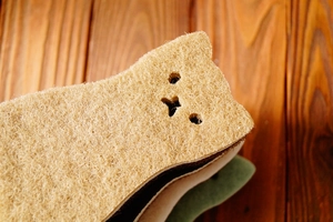 Close-up of cat-shaped dishwashing sponge showing multi-layer fiber texture on wood table