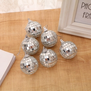 Close-up of six small silver disco mirror balls with reflective glass tiles on wood surface