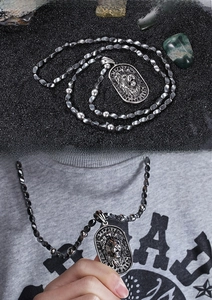 Detailed relief of a punk lion head pendant on a textured black and silver bead chain