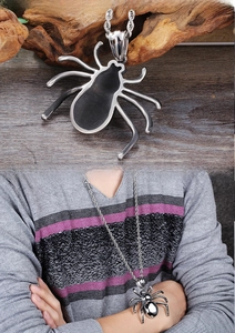 Macro detail of a silver spider pendant with a thick rope chain on a wooden surface