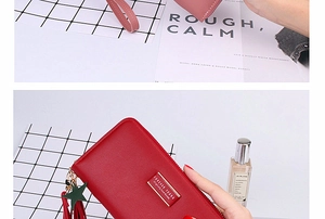 Detail of long zippered wallet with litchi texture, star pendant and tassel zipper puller
