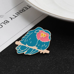 Cartoon enamel bird brooch featuring blue and pink bird on a gold branch for clothing