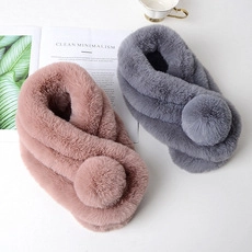 Detailed close-up of pink and grey plush scarves featuring soft faux fur pompom details