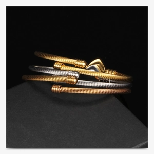 Dettaglio macro di bracciali a cavo intrecciato in oro, argento e oro rosa lucido