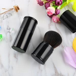 Detail of portable black retractable makeup brush with cap on marble background