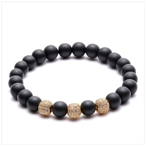 Macro view of 8mm matte black stone beads with gold micro-pave zircon charms on bracelet