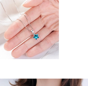 Detail of silver necklace with blue pentagram star crystal pendant on model's neck