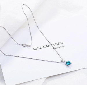 Macro shot of silver box chain and light blue star crystal pendant with spring clasp