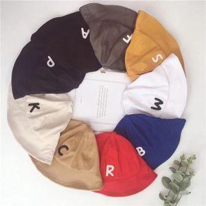 Flat lay of colorful children bucket hats with letter embroidery on soft fabric
