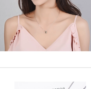 Close-up of a silver chain featuring a light green water-drop pendant on a female model