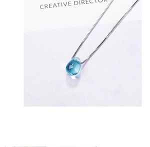 Macro detail of a light blue water drop crystal pendant with a silver box chain