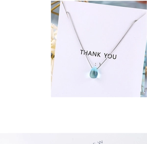 Detailed view of an elegant light blue teardrop crystal pendant on a silver metal chain
